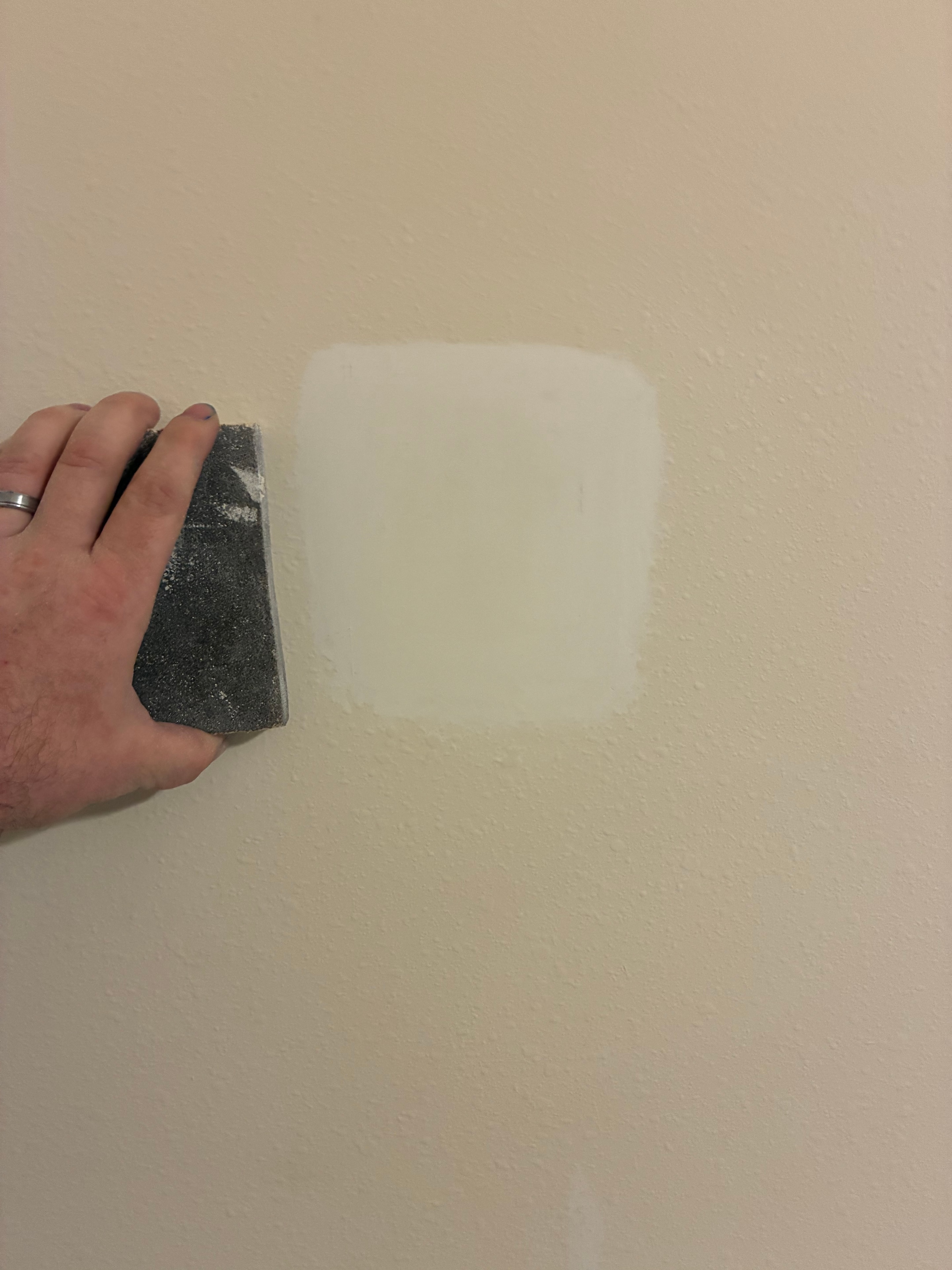 Drywall patch being sanded smooth